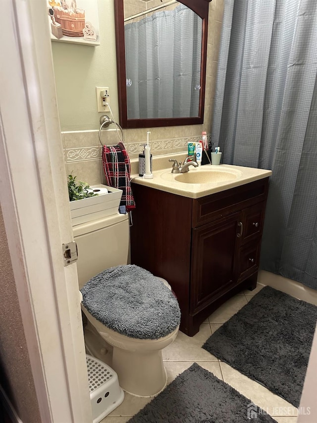 bathroom with toilet, vanity, and tile patterned flooring