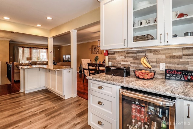 kitchen with wine cooler, ornamental molding, decorative columns, and white cabinets