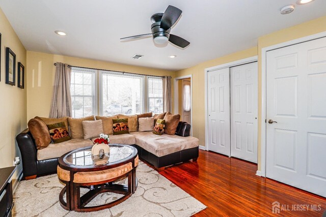 living room featuring dark wood-type flooring and ceiling fan