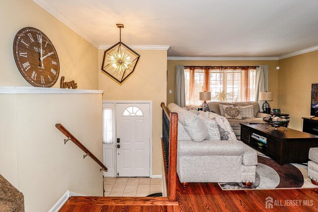 entryway with crown molding, a chandelier, and light wood-type flooring