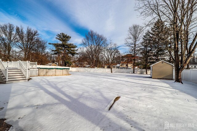 snowy yard featuring a shed and a covered pool