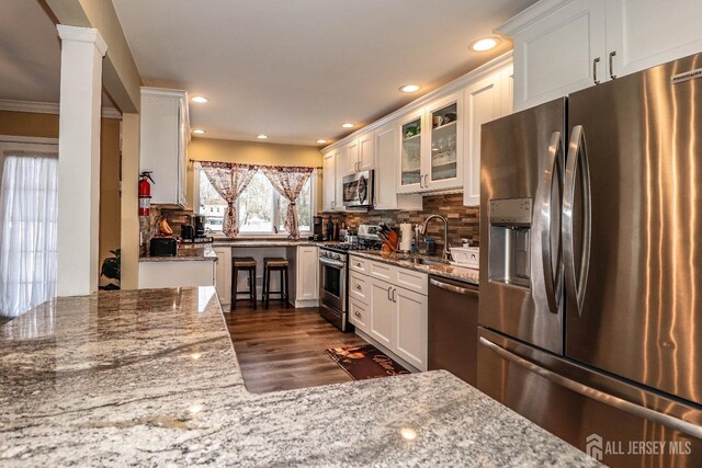 kitchen with sink, appliances with stainless steel finishes, tasteful backsplash, white cabinets, and stone countertops