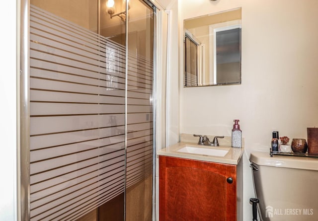 bathroom featuring vanity, a shower with shower door, and toilet