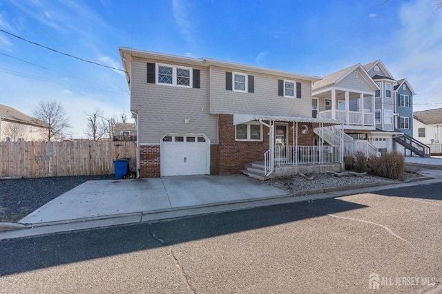 view of front of house featuring brick siding, fence, concrete driveway, stairs, and a garage