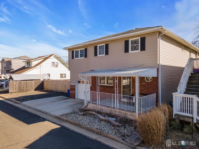 318 Bayview Ave, Union Beach, NJ 07735 - traditional-style house featuring a porch, an attached garage, concrete driveway, brick siding, and stairs