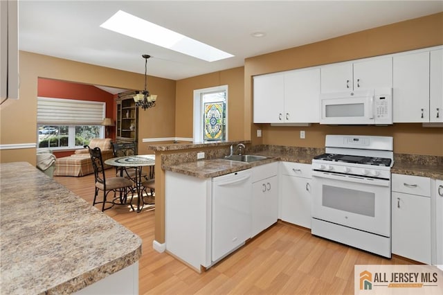 kitchen featuring white appliances, a peninsula, a sink, white cabinets, and light wood-type flooring