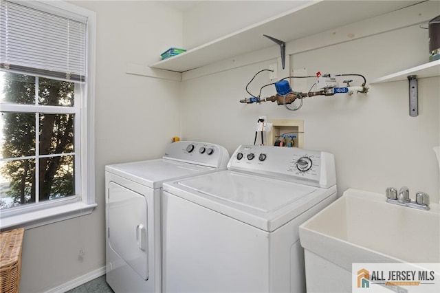 washroom with washer and clothes dryer, laundry area, baseboards, and a sink