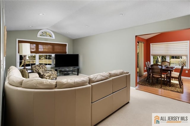 living room featuring light carpet, baseboards, and vaulted ceiling