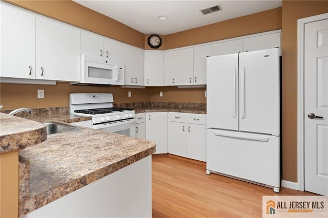 kitchen with light wood finished floors, visible vents, white cabinets, white appliances, and a sink