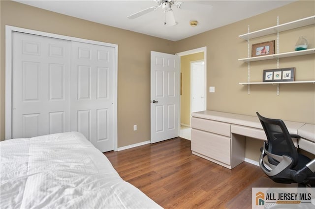 bedroom featuring dark wood-type flooring, a closet, baseboards, ceiling fan, and built in study area