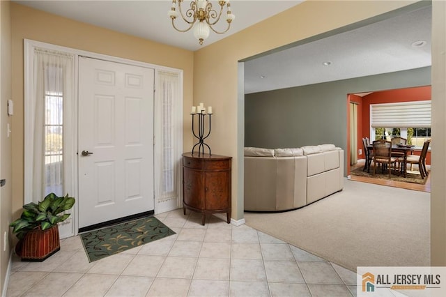 entryway with a chandelier, light tile patterned floors, light carpet, and baseboards