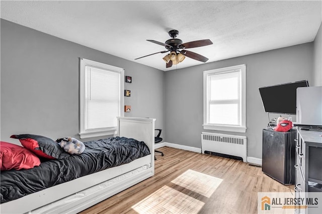 20 Cedar Ave, North Brunswick, NJ 08902 - bedroom with radiator heating unit, light wood-type flooring, baseboards, and ceiling fan