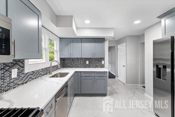 2164 Whitehorse Hamilton Square Rd, Hamilton, NJ 08690 - kitchen featuring appliances with stainless steel finishes, light marble finish floors, gray cabinetry, backsplash, and light stone countertops