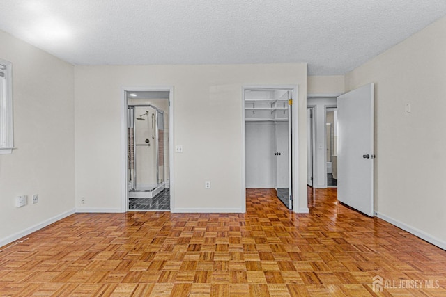 553-N Tilton Way, Monroe, NJ 08831 - unfurnished bedroom with baseboards, a spacious closet, a textured ceiling, ensuite bathroom, and a closet