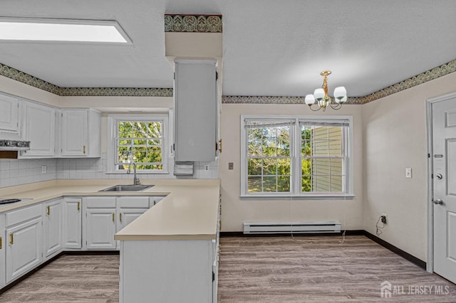 553-N Tilton Way, Monroe, NJ 08831 - kitchen with a baseboard heating unit, a sink, a chandelier, backsplash, and white cabinetry