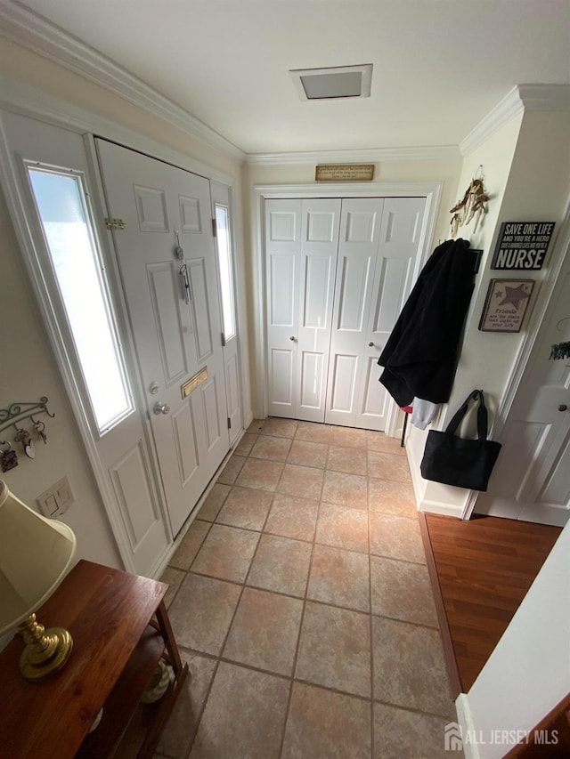 entryway featuring light tile patterned floors and ornamental molding