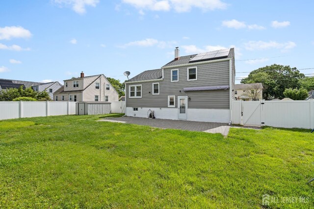 315 D St, Middlesex, NJ 08846 - back of property featuring a gate, a patio, solar panels, and a chimney