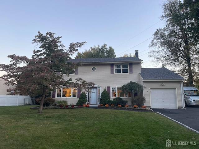 colonial-style house featuring a garage and a front lawn