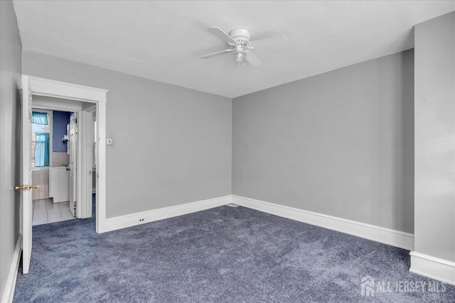 empty room with dark colored carpet and ceiling fan