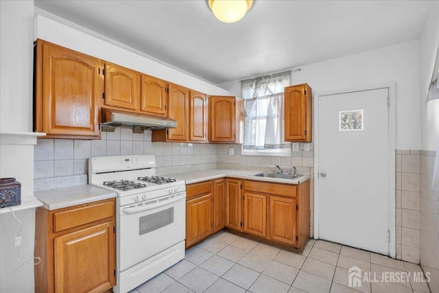 kitchen with light tile patterned flooring, sink, and gas range gas stove