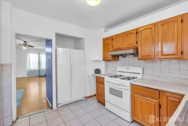 kitchen featuring white appliances, light hardwood / wood-style flooring, ceiling fan, and backsplash