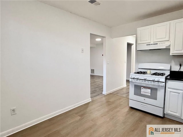 kitchen featuring white range with gas stovetop, white cabinets, and light hardwood / wood-style floors