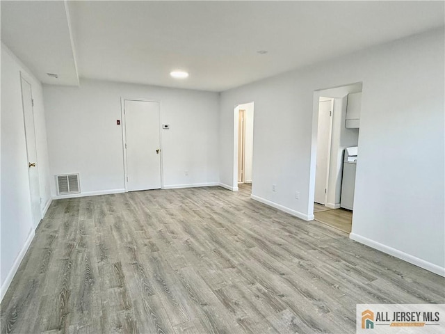 unfurnished room featuring washer / clothes dryer and light hardwood / wood-style floors