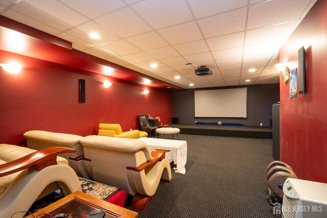 carpeted cinema room with a drop ceiling