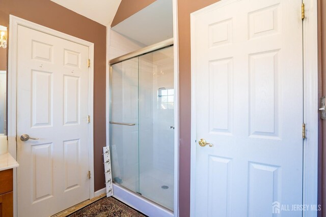 bathroom with vanity, a shower with shower door, and lofted ceiling