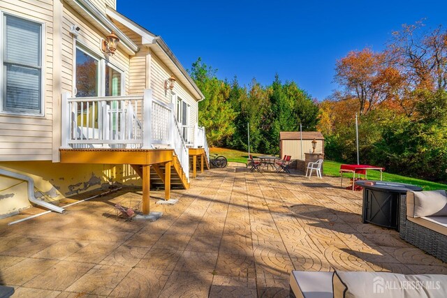 wooden deck featuring a storage shed and a patio area