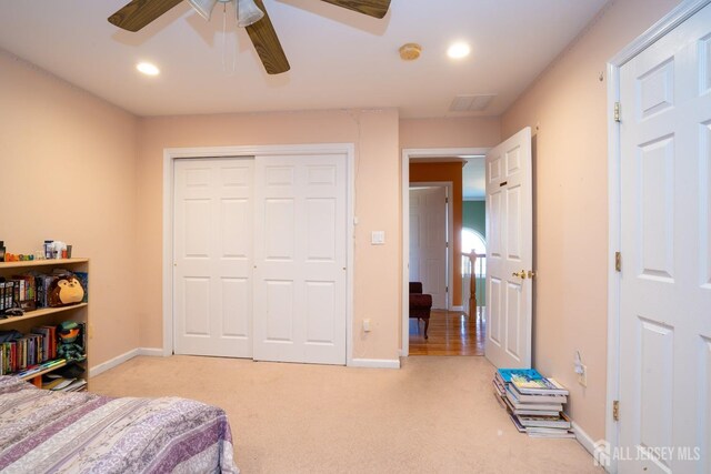 carpeted bedroom featuring ceiling fan and a closet