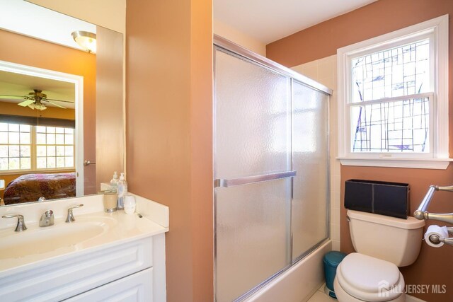 full bathroom with sink, enclosed tub / shower combo, toilet, and ceiling fan