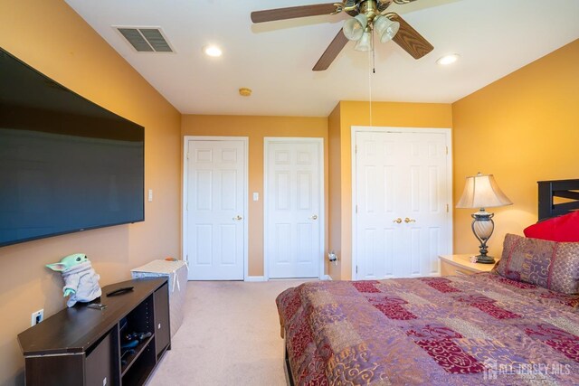 carpeted bedroom with multiple closets and ceiling fan