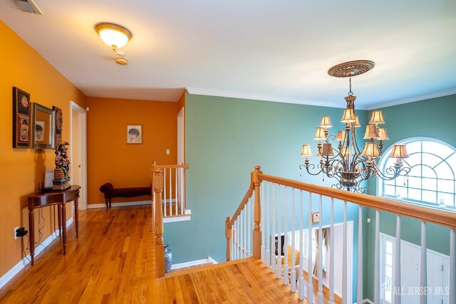 hall featuring crown molding, wood-type flooring, and a chandelier