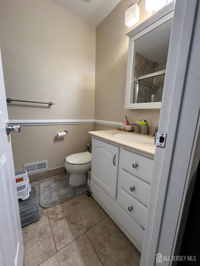 bathroom with vanity, toilet, tile patterned flooring, and a shower with door