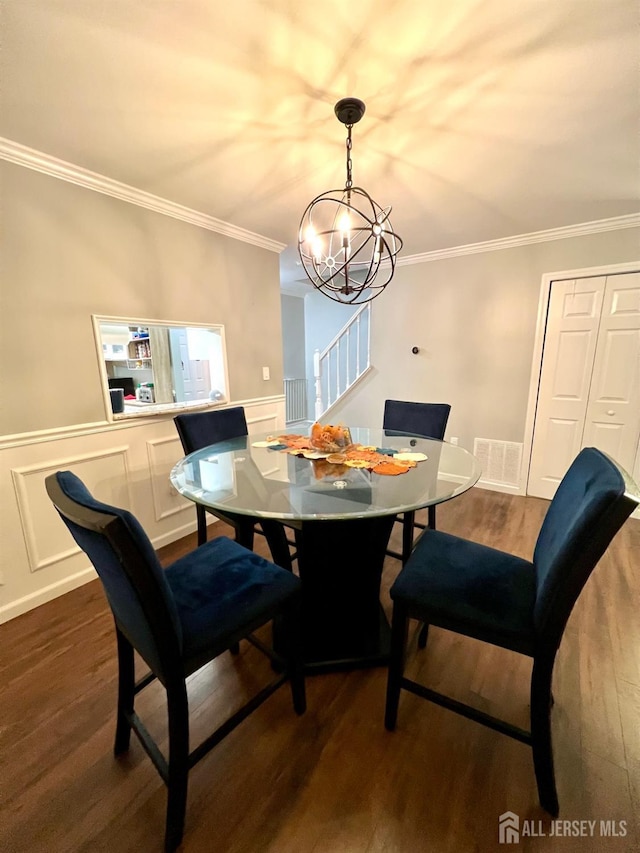 dining space featuring hardwood / wood-style flooring, ornamental molding, and a notable chandelier