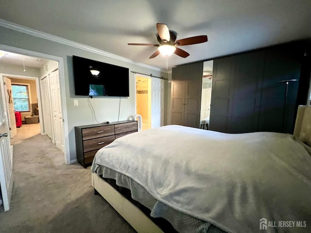 bedroom featuring crown molding, ceiling fan, a barn door, and light colored carpet