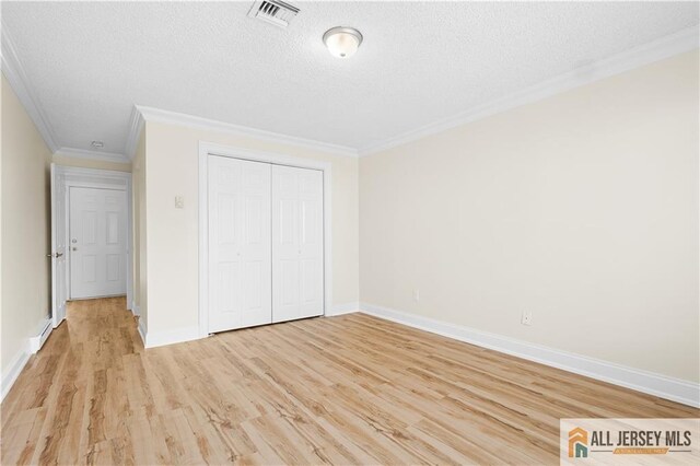 unfurnished bedroom featuring crown molding, light hardwood / wood-style floors, a closet, and a textured ceiling