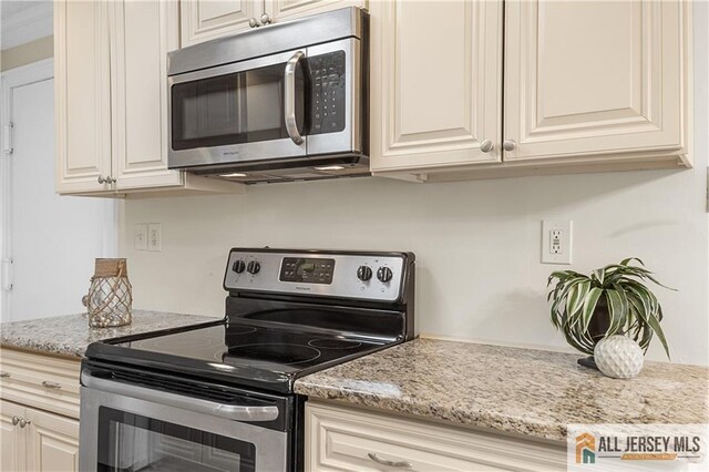 kitchen with light stone counters, cream cabinets, and stainless steel appliances