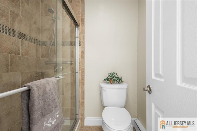 bathroom with tile patterned flooring, a shower with shower door, toilet, and baseboard heating