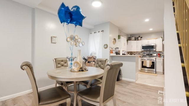 dining room featuring light wood-style flooring, recessed lighting, and baseboards