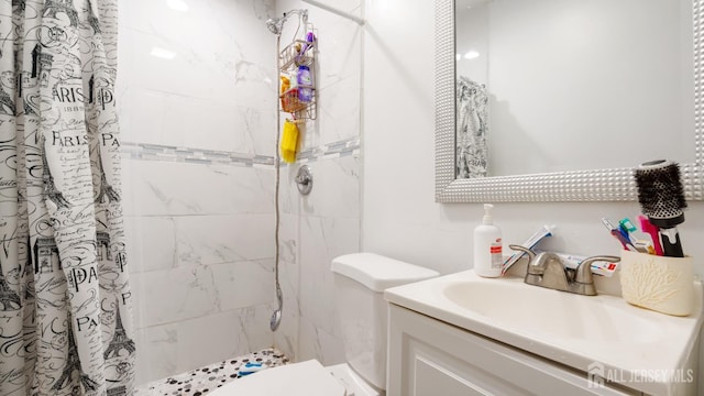 bathroom featuring a tile shower, toilet, and vanity
