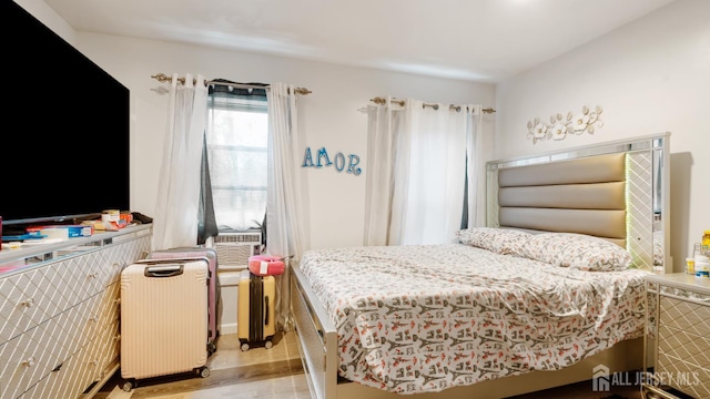 bedroom featuring wood finished floors, radiator heating unit, and cooling unit