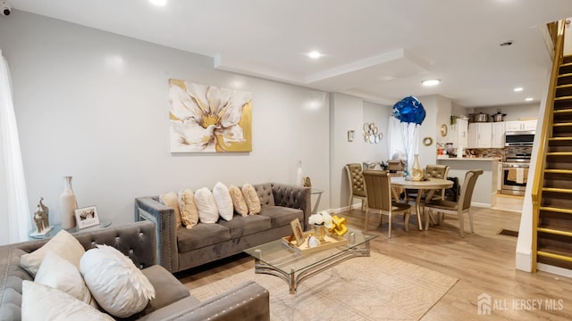 living area featuring light wood-type flooring, stairs, and recessed lighting