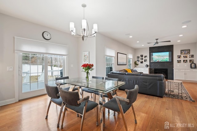 dining area with baseboards, light wood-style flooring, recessed lighting, a fireplace, and ceiling fan with notable chandelier