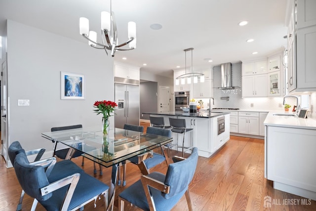 dining room featuring recessed lighting, light wood-style flooring, and an inviting chandelier