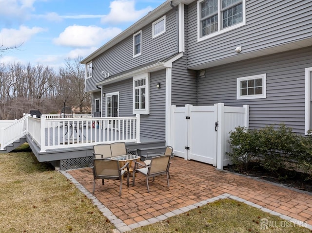 rear view of property featuring fence, an outdoor fire pit, a wooden deck, a patio area, and a lawn