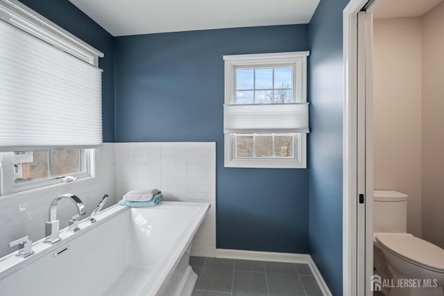 bathroom with a bathtub, tile patterned floors, toilet, and baseboards