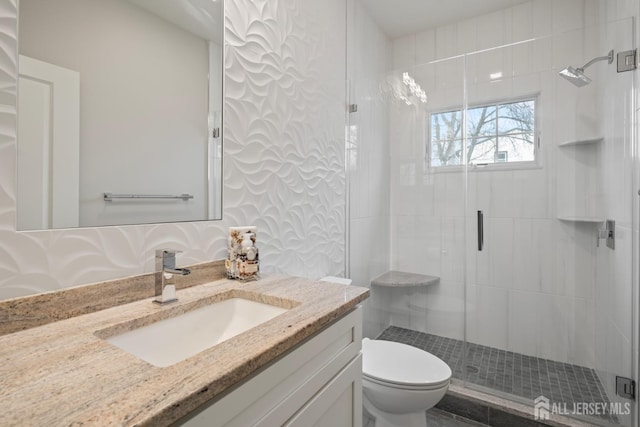 bathroom featuring vanity, a shower stall, and toilet