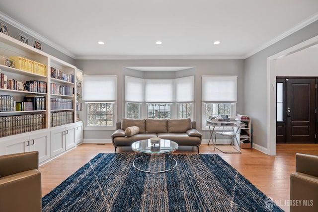 living area featuring baseboards, light wood finished floors, and ornamental molding